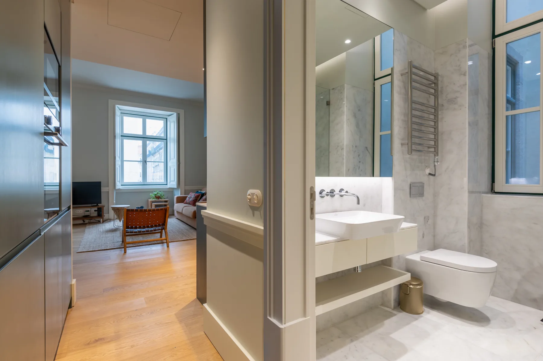 Un baño con lavabo e inodoro se abre a una sala de estar con asientos.