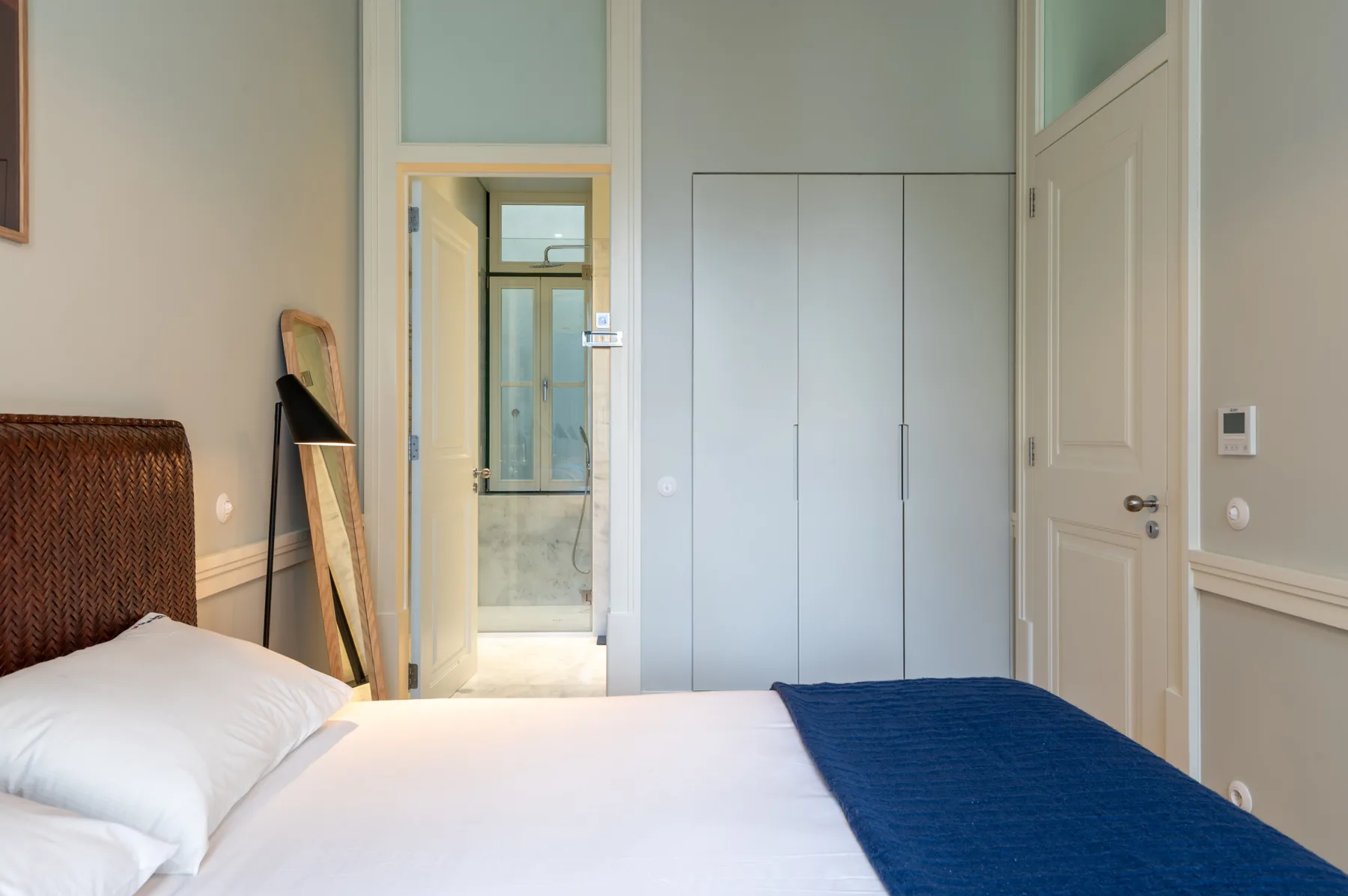 Un dormitorio con la cama arreglada y una puerta que da a un baño.