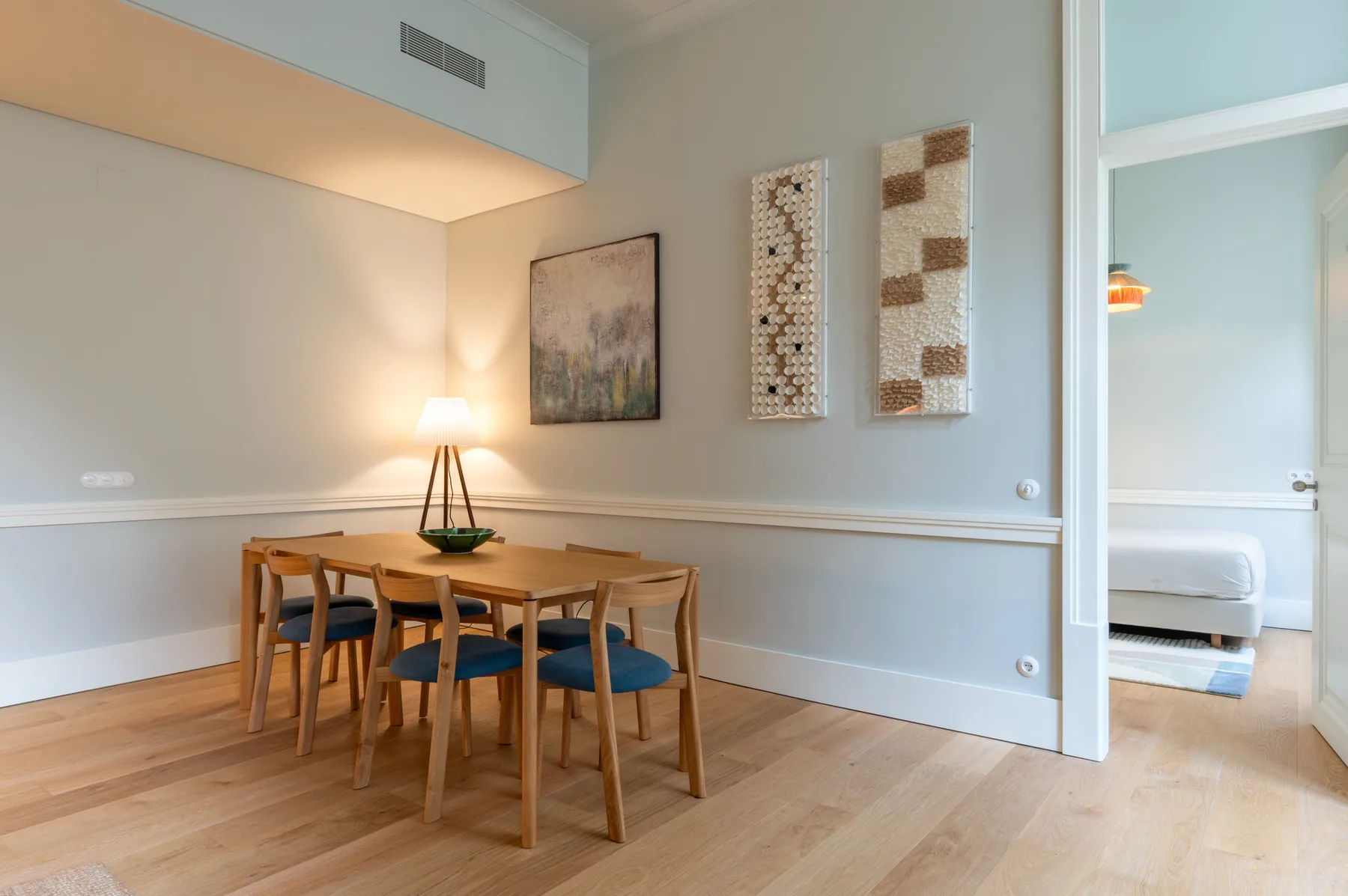 Comedor con una mesa de madera y sillas bajo cuadros decorativos.