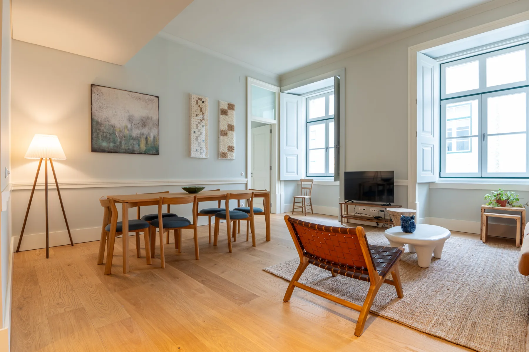 Un salón-comedor luminoso con una mesa de madera y asientos.