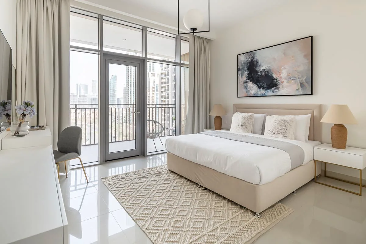 Un dormitorio luminoso con una cama grande junto a ventanales.