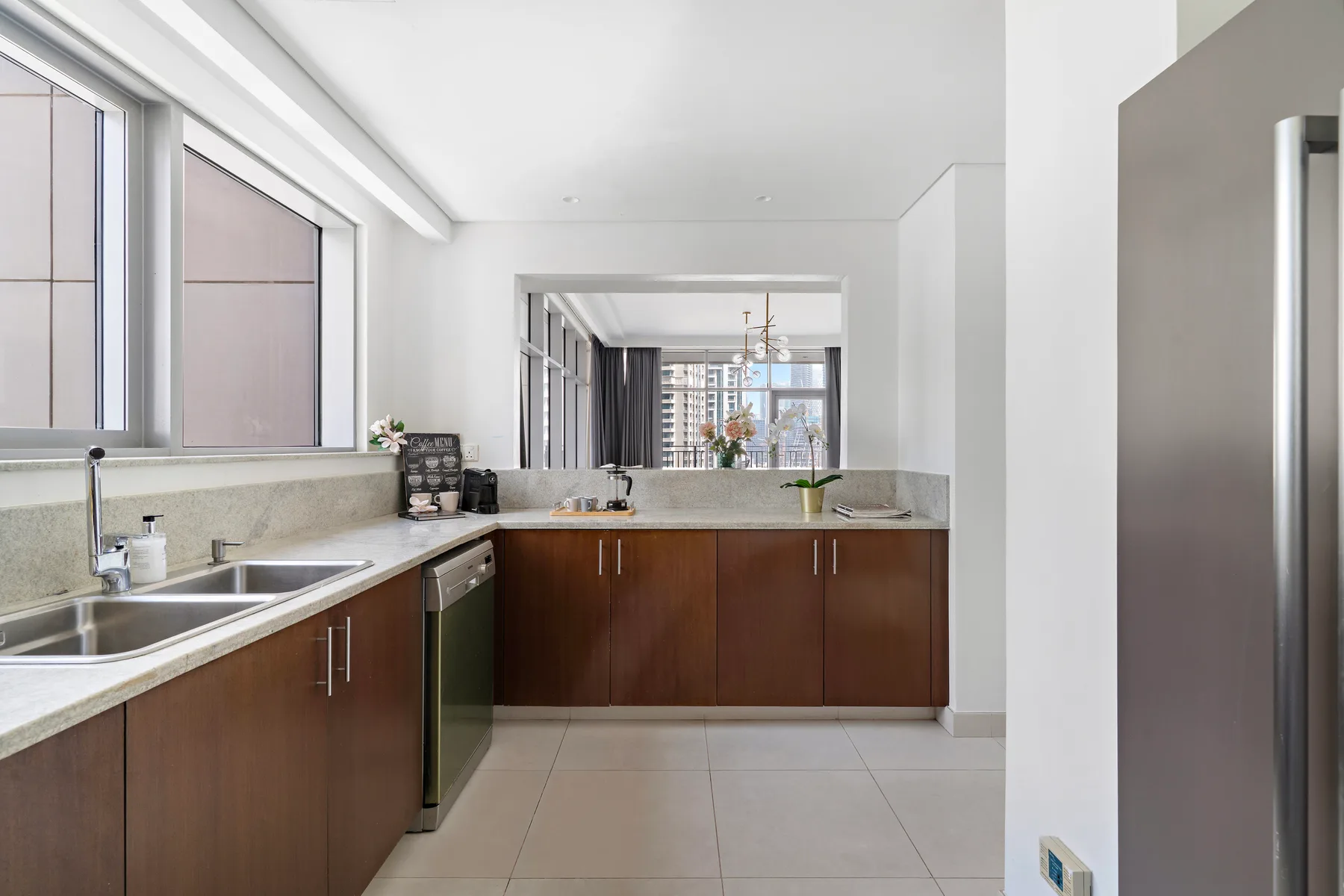 Una cocina moderna con gabinetes oscuros y una encimera bajo grandes ventanas.