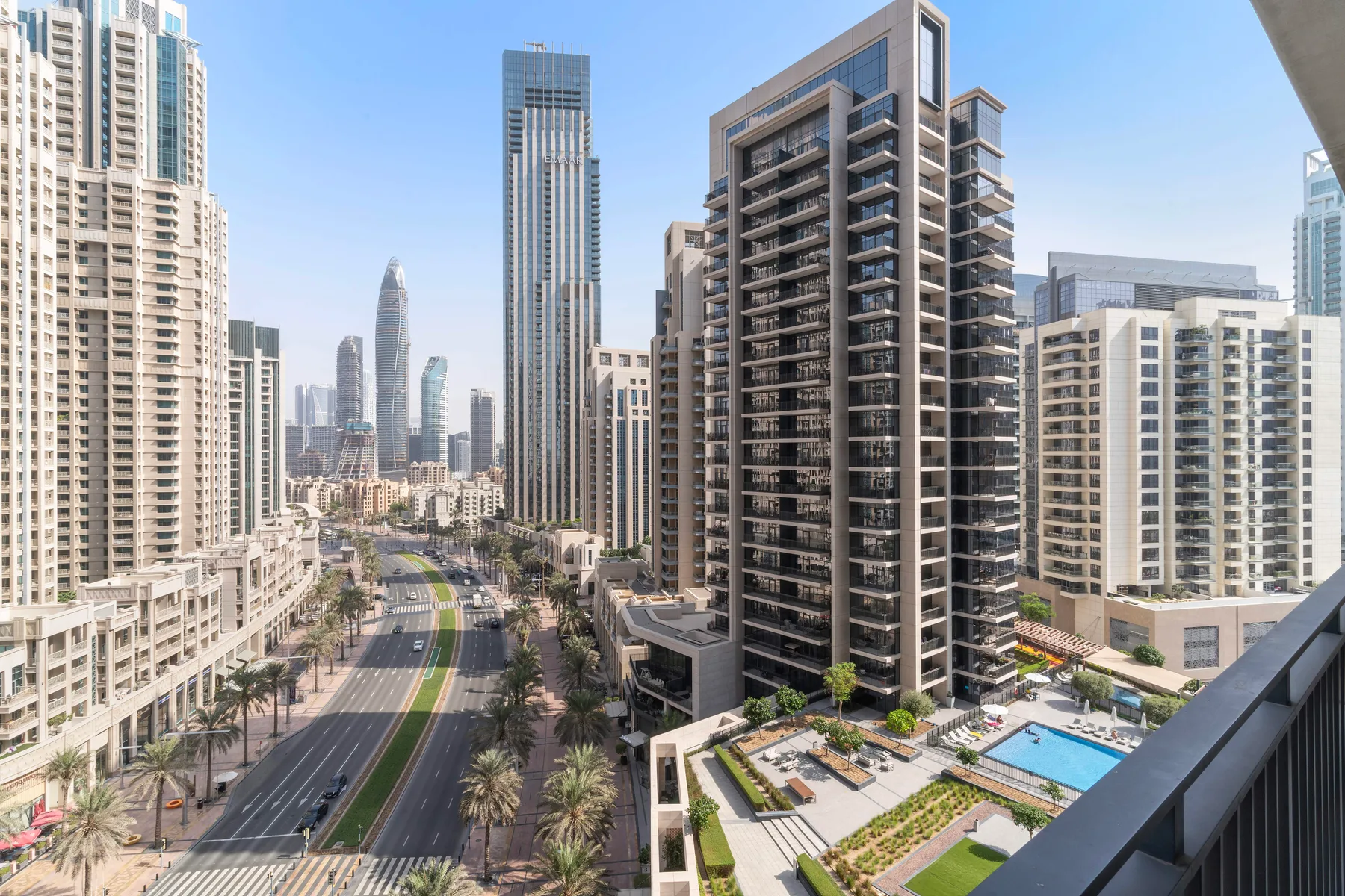 Vista urbana de edificios altos junto a una avenida bordeada de palmeras.