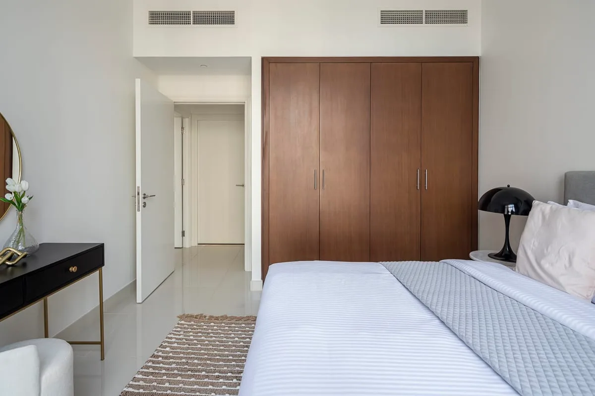 Un dormitorio con una cama junto a un armario grande de madera.