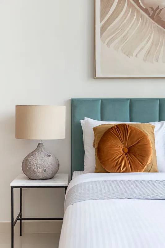 Un dormitorio con una cama bien tendida y una mesa de noche.