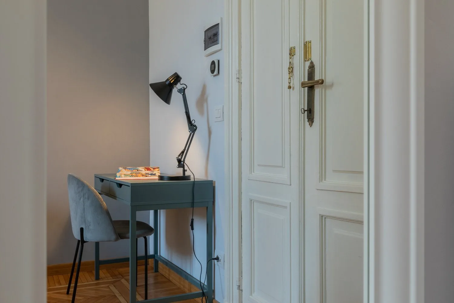 A small desk and seating sit beside a white paneled door.