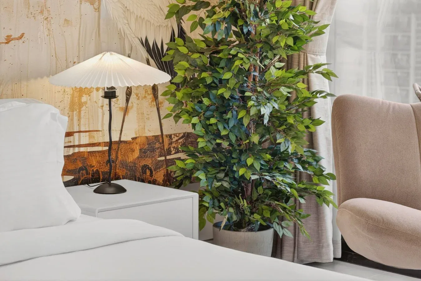 A bedroom with a bed, a floor lamp, and a leafy potted plant.