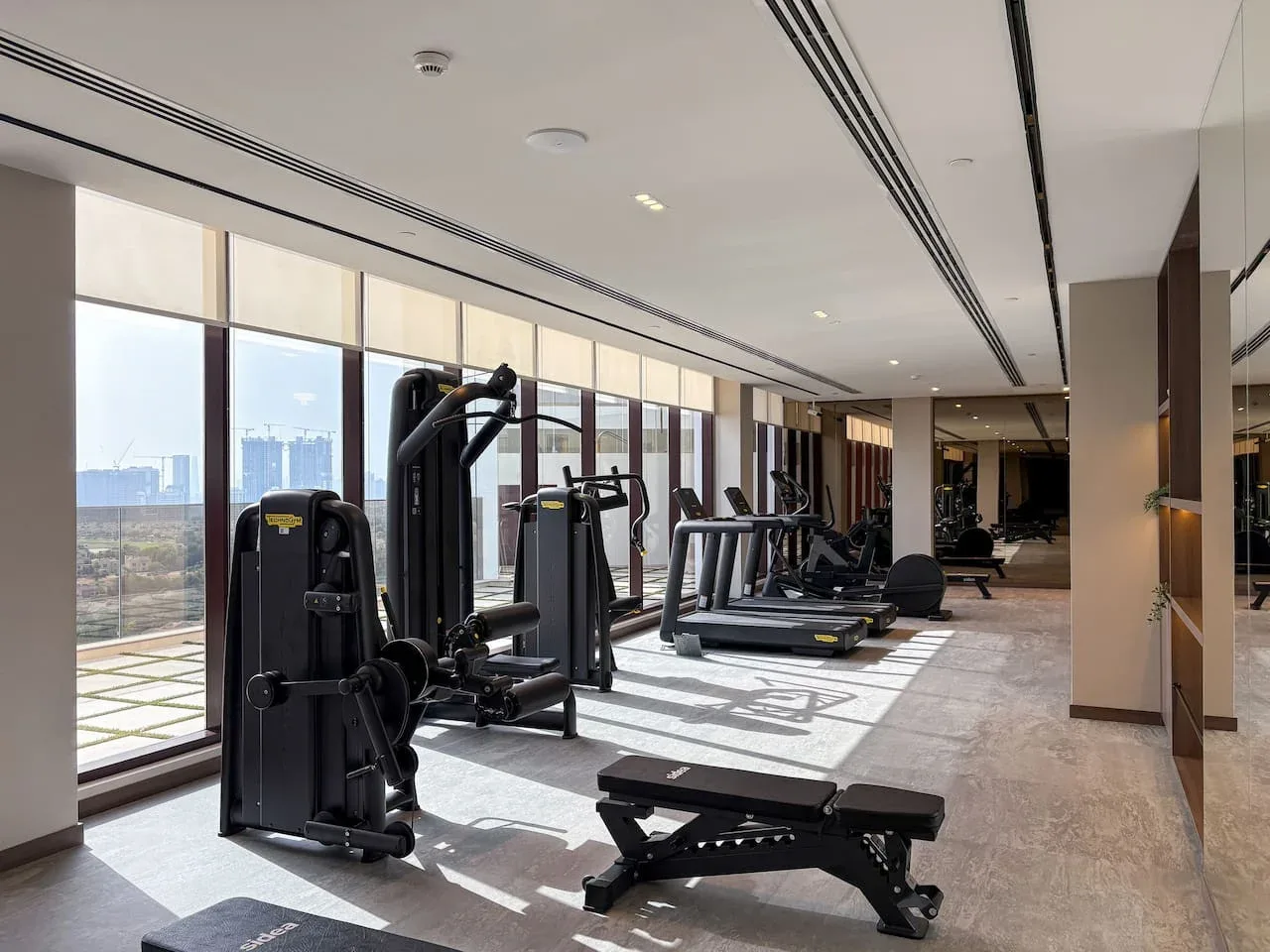 A bright gym with exercise machines and large windows.