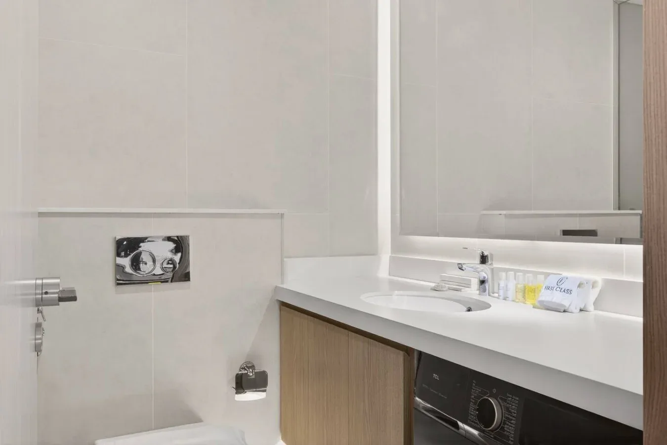 A bright bathroom vanity with a mirror and a washing machine beneath the counter.
