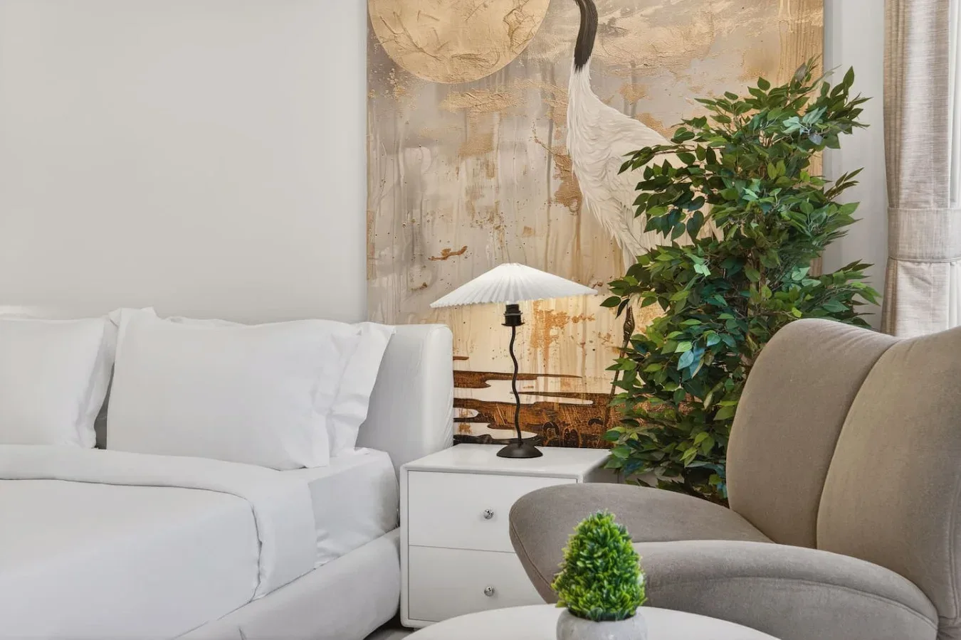 A living room with white seating, a side table, and a leafy plant.