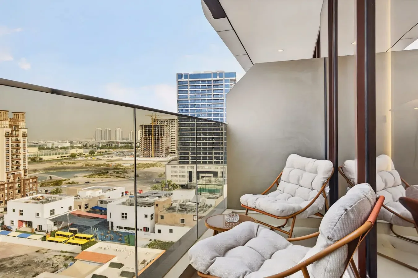 A balcony seating area overlooks nearby buildings and a broad urban landscape.