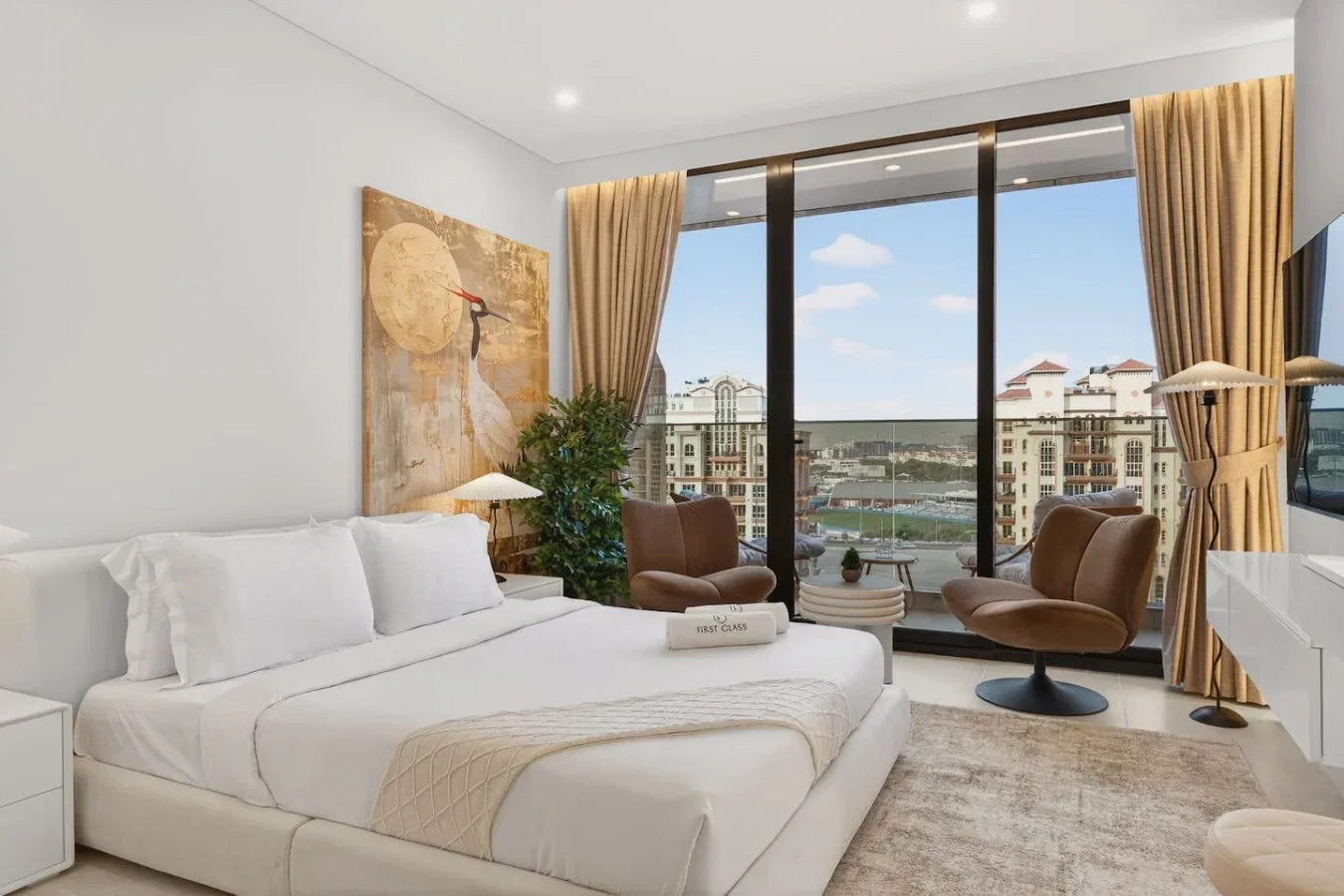A bright bedroom with a bed and seating beside large windows.