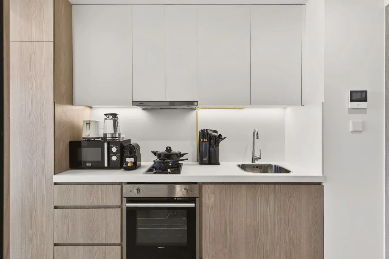 A modern kitchen with light cabinetry, a cooktop, and a sink.