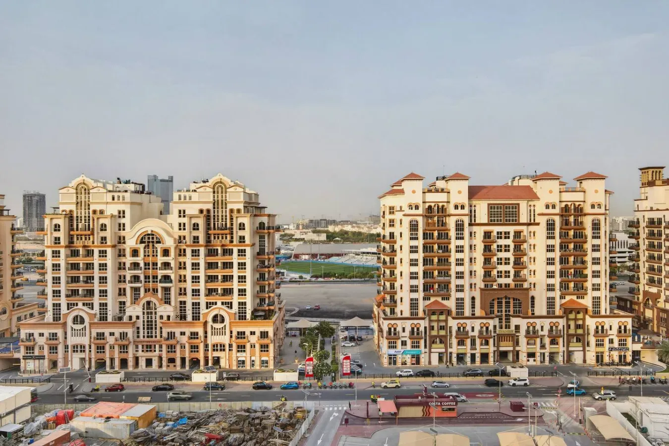 A city view shows two large apartment buildings beside a busy road.