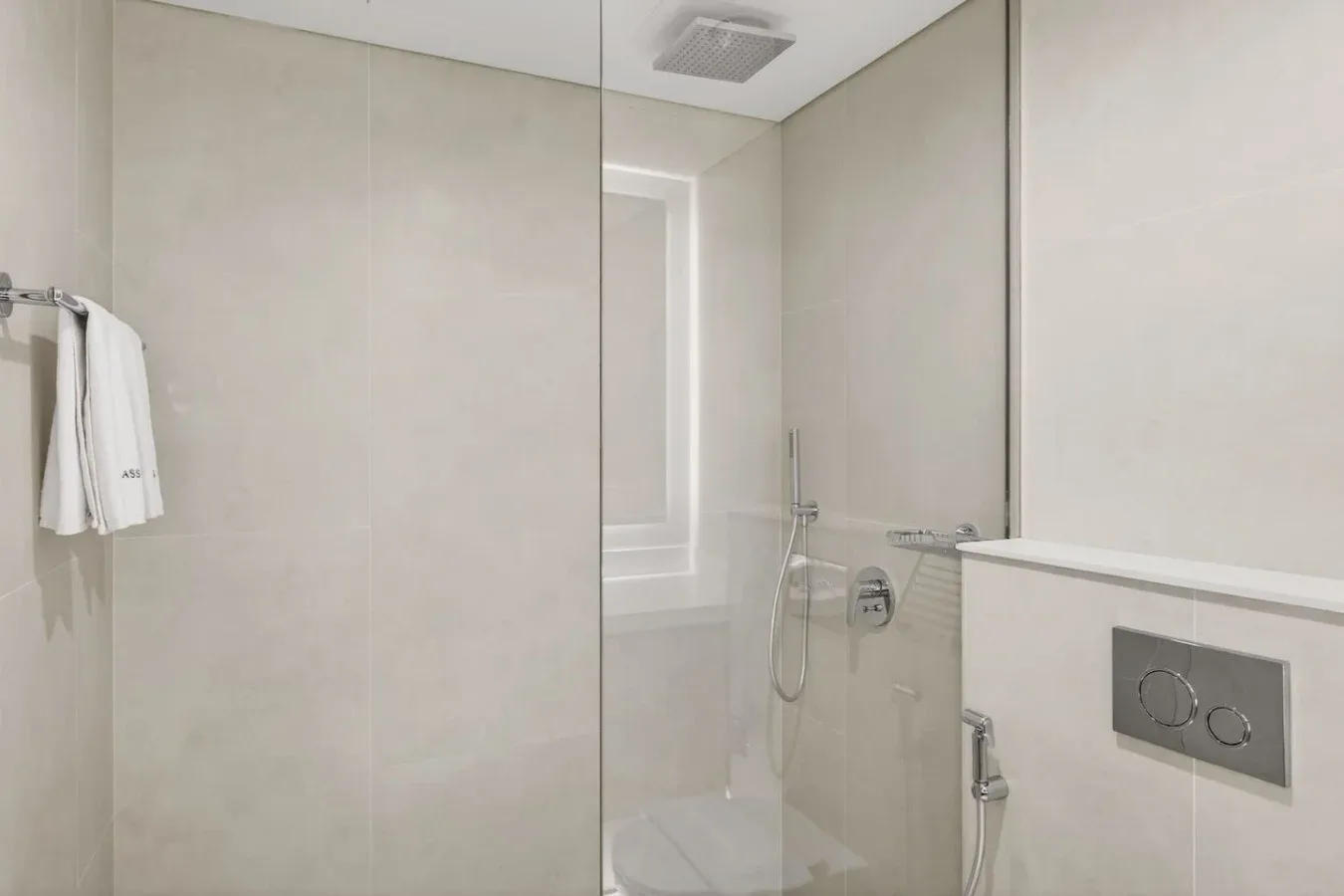 A bright tiled bathroom with a shower and wall-mounted towel rail.