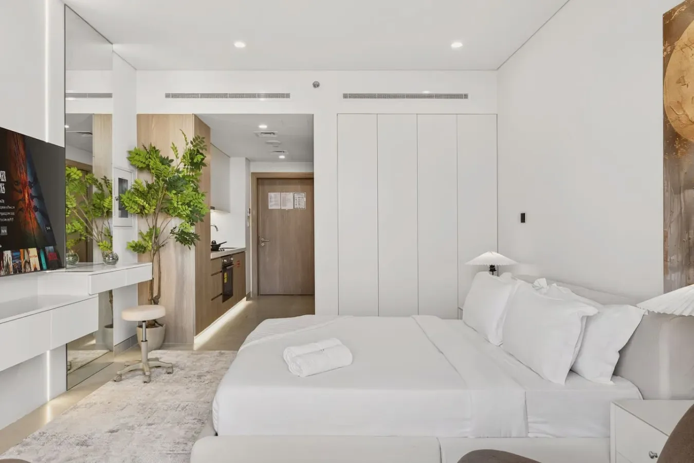 A bright bedroom with a neatly made bed and white bedding.