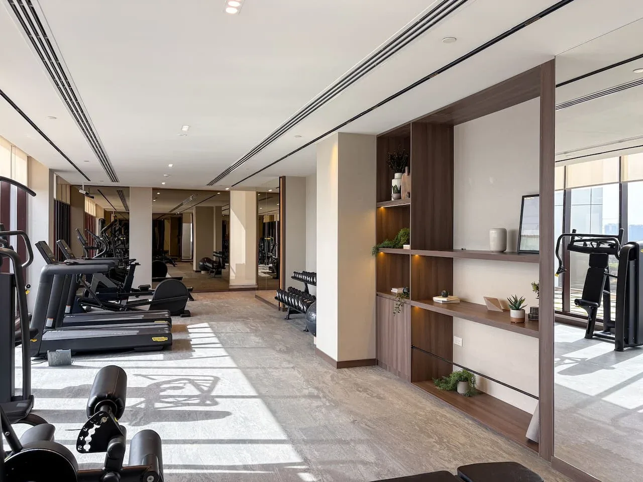 A gym with exercise equipment and a built-in shelving unit along the wall.