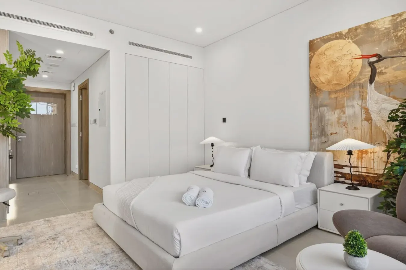 A bright bedroom with a neatly made bed and large wall artwork.