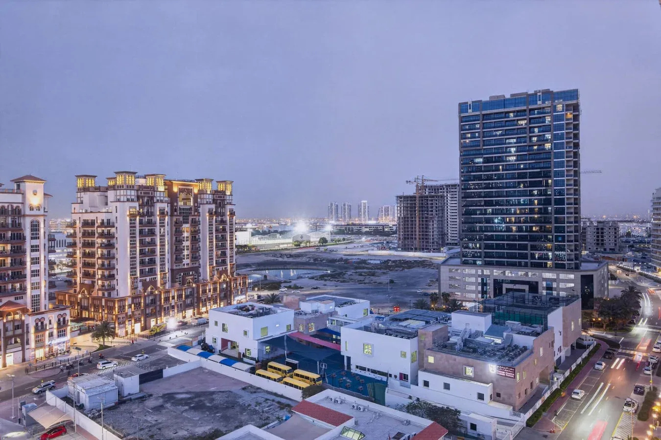A cityscape at dusk with apartment buildings and a taller office tower.