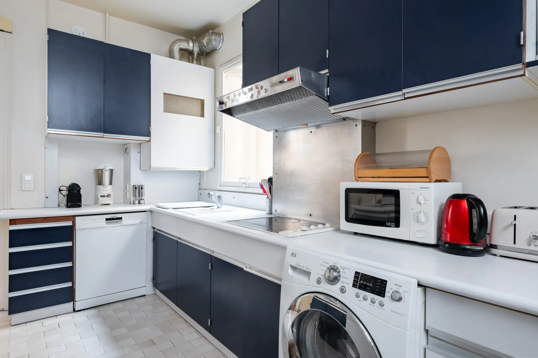 Una cocina compacta con armarios oscuros, fregadero y electrodomésticos sobre la encimera.