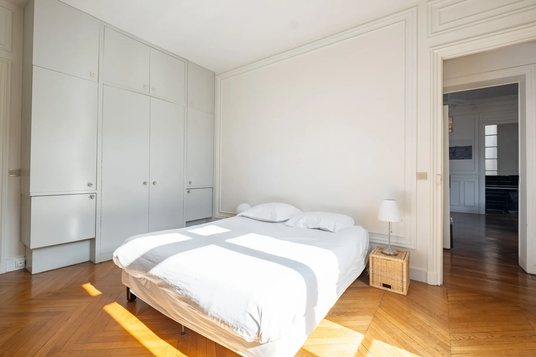 Un dormitorio luminoso con una cama y armarios empotrados junto a la pared.