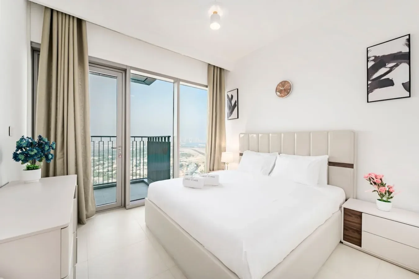 A bright bedroom with a large bed beside glass doors opening onto a balcony.