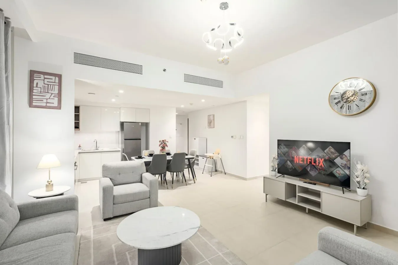 Una sala luminosa se abre a un comedor, con televisor y asientos.