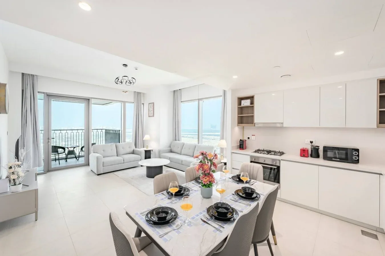Una luminosa sala-comedor de planta abierta, con cocina blanca y vistas al mar.