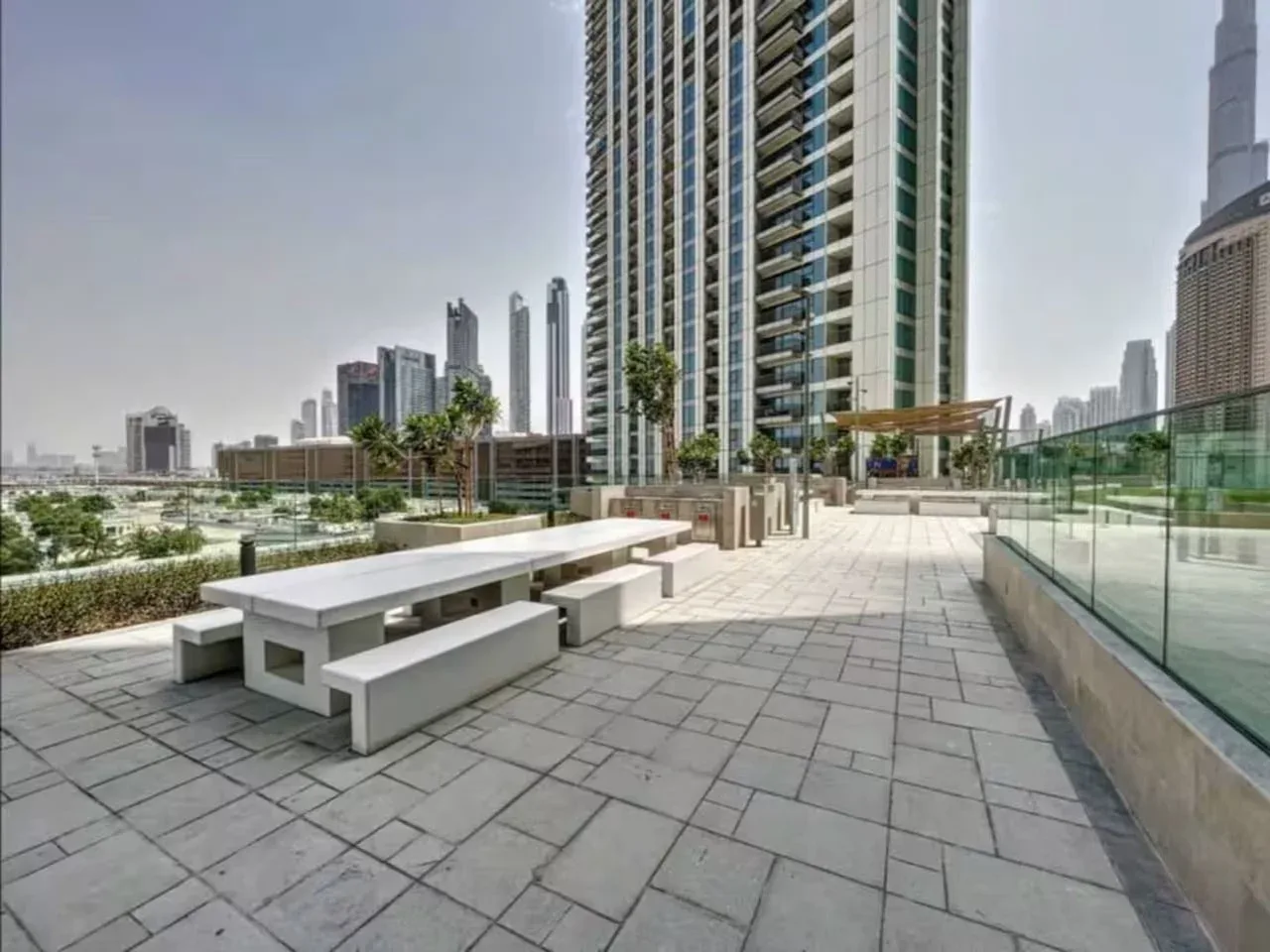 Una terraza al aire libre con una mesa larga, asientos y el horizonte de la ciudad.
