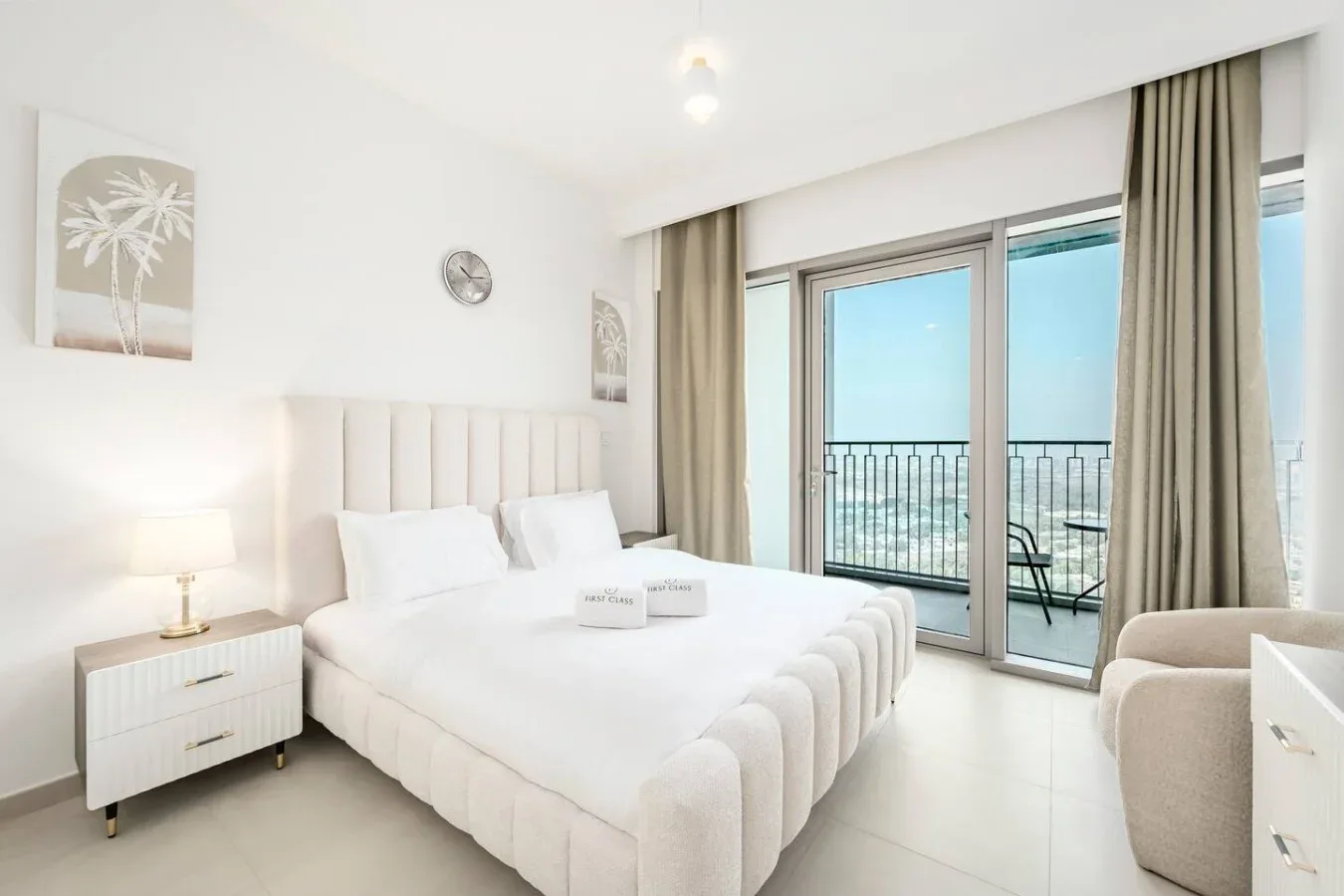 Un dormitorio luminoso con una cama grande junto a puertas de vidrio que dan a un balcón.