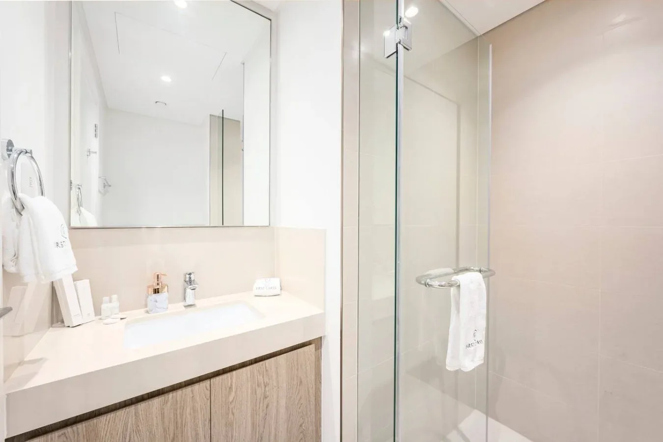 Un baño luminoso con un amplio tocador y una ducha de vidrio.
