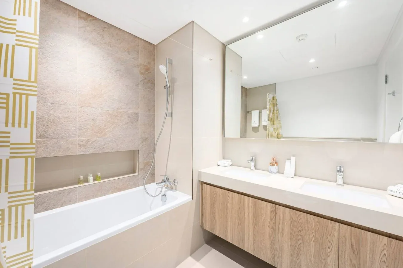 Un baño con bañera, ducha y un largo tocador bajo un espejo.