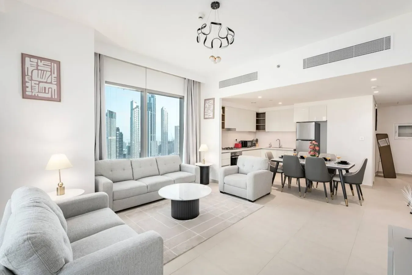 Una luminosa sala de estar se conecta con el comedor y la cocina, junto a grandes ventanas con vistas a edificios.