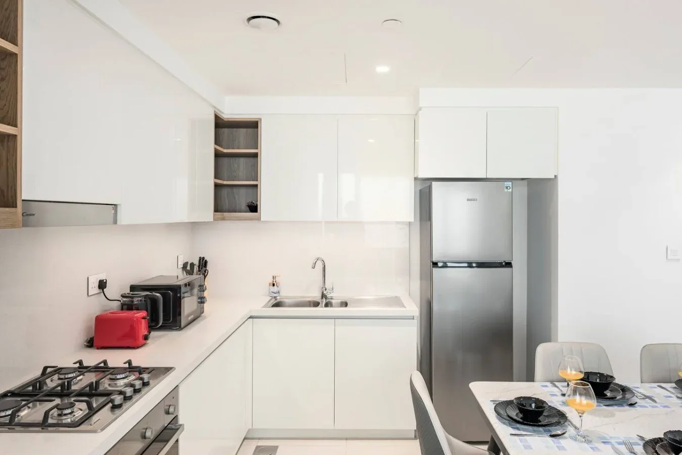 Una cocina moderna y luminosa con gabinetes blancos, una encimera y electrodomésticos de acero inoxidable.