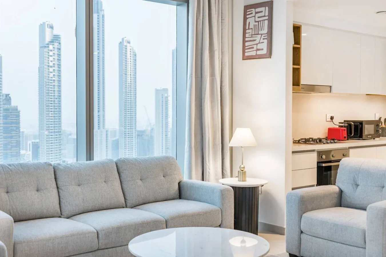 Una sala luminosa con asientos grises junto a grandes ventanas con vistas a la ciudad.