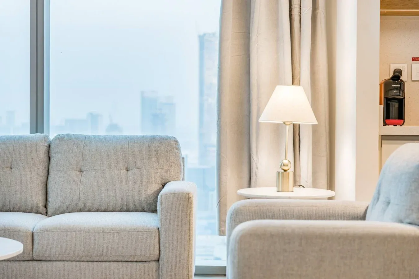 Una sala luminosa con asientos junto a una ventana grande y una lámpara de pie.