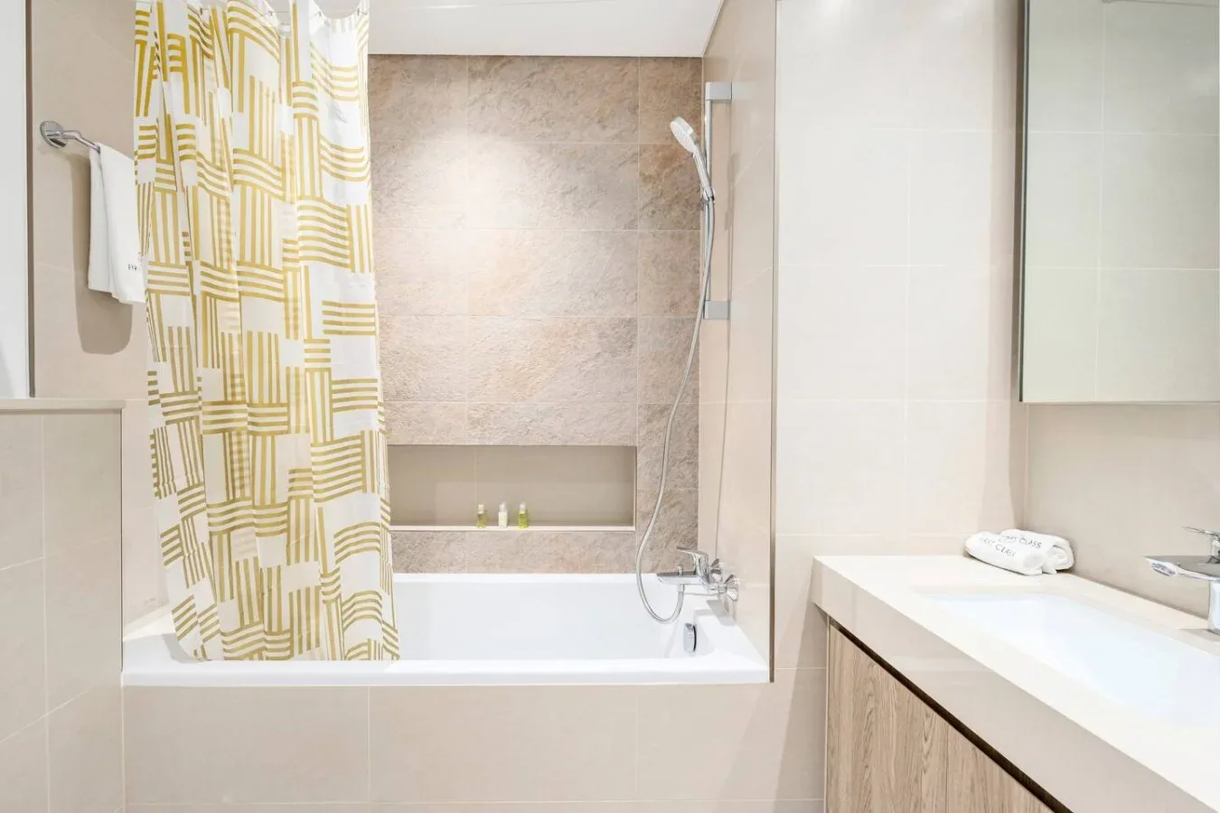 Un baño con bañera, cortina de ducha estampada y tocador.