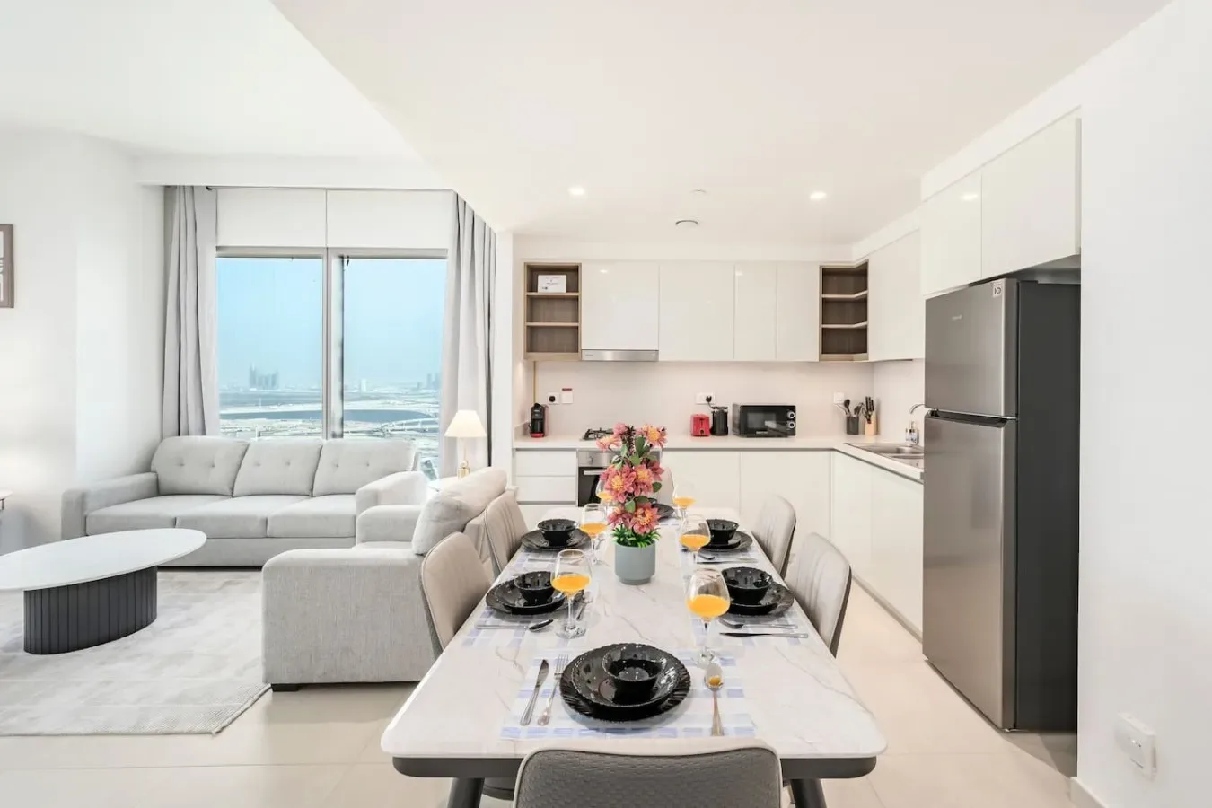 A bright open-plan living and dining area with a kitchen and a set dining table.