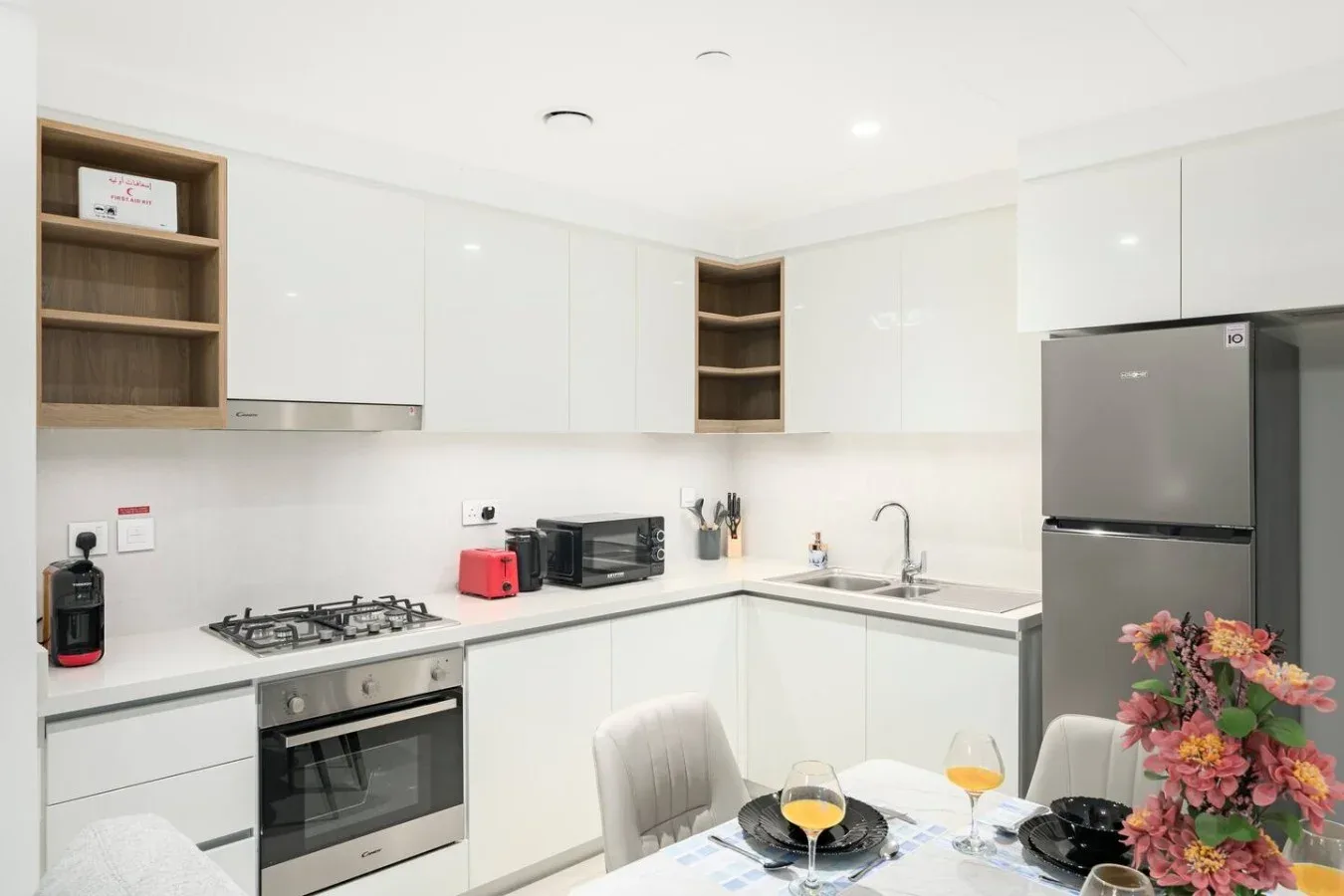 Una cocina moderna y luminosa con gabinetes blancos, una estufa de gas y un refrigerador.