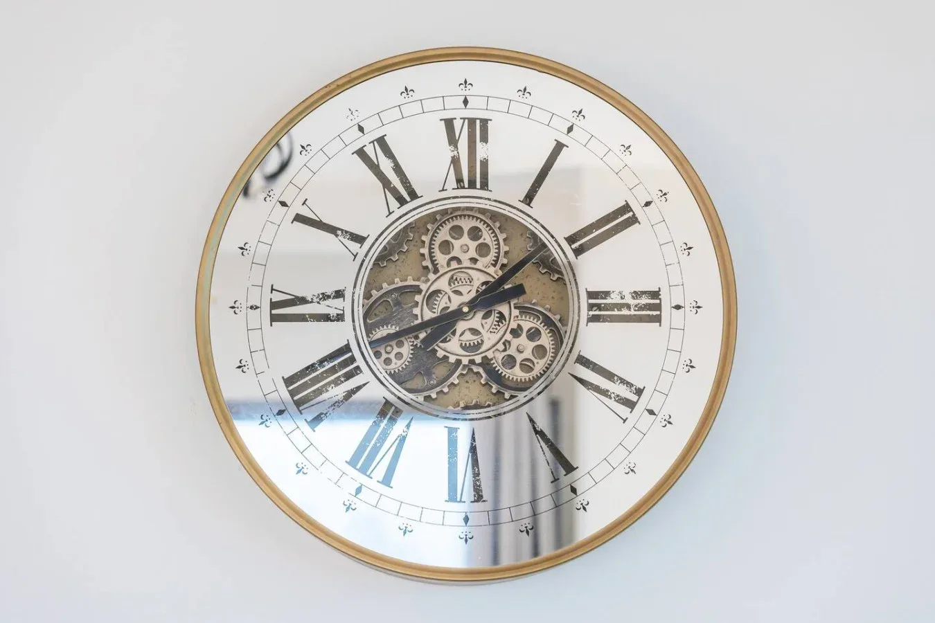 Un reloj de pared grande con números romanos y engranajes visibles.