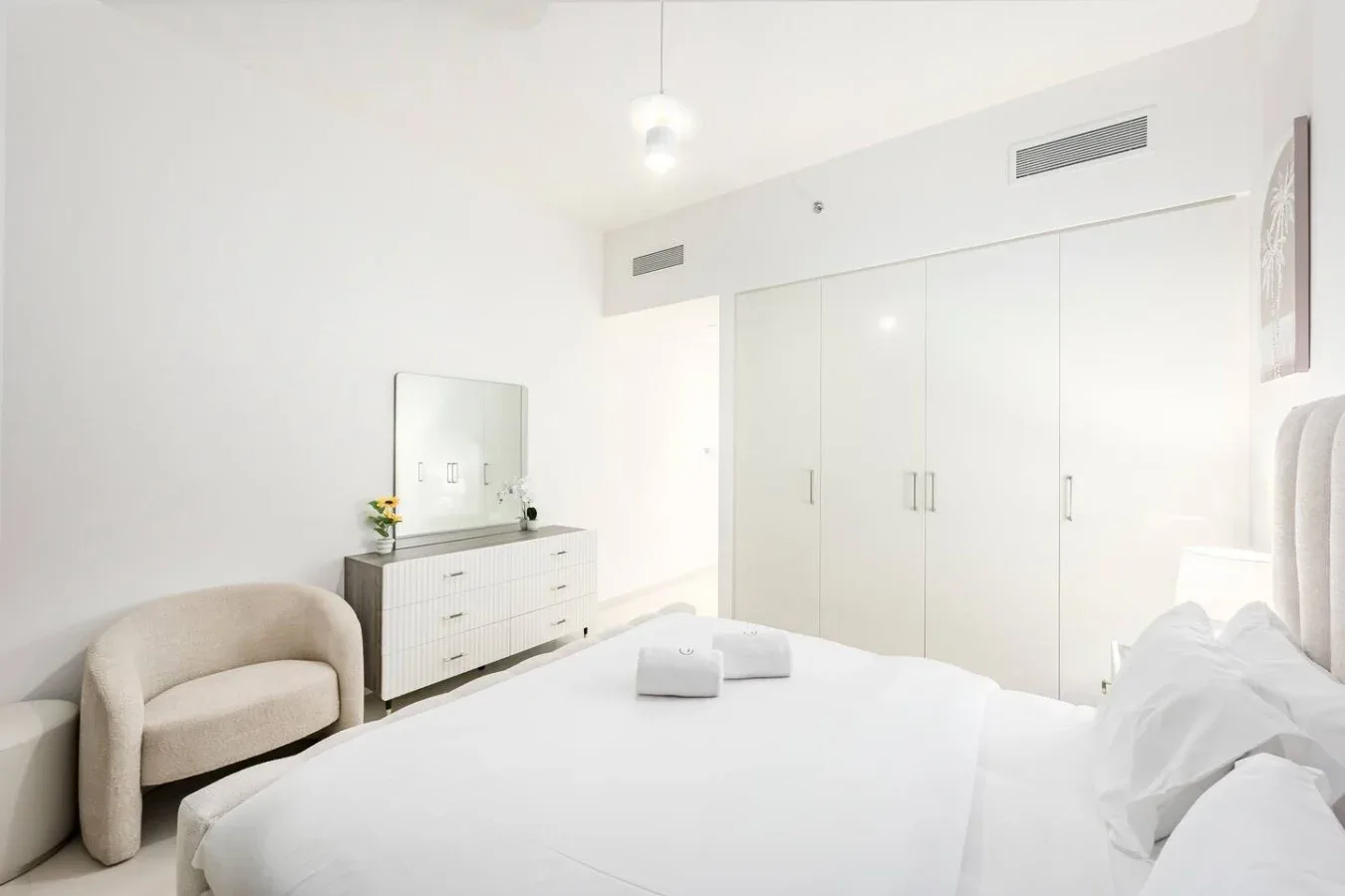 Un dormitorio luminoso con una cama, una cómoda y armarios empotrados.