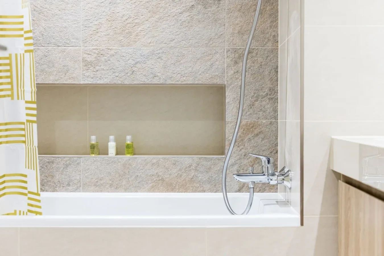 Un baño con bañera, ducha de mano y cortina estampada.