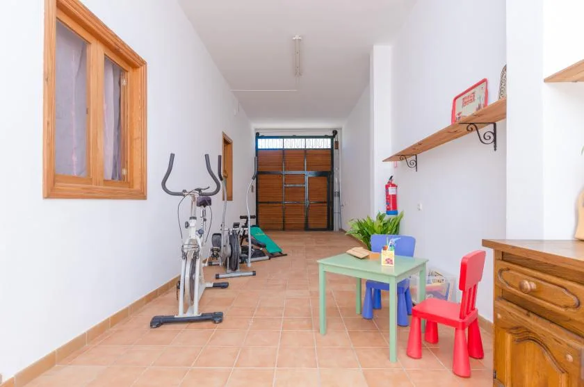 A small exercise and play area has fitness equipment, a children’s table, and colorful chairs.