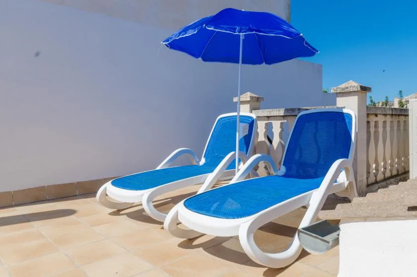An outdoor patio with blue lounge seating beneath a matching umbrella.