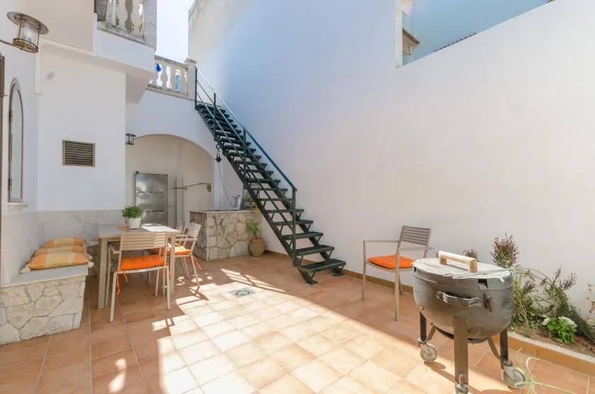 A bright courtyard patio with a staircase and outdoor seating.