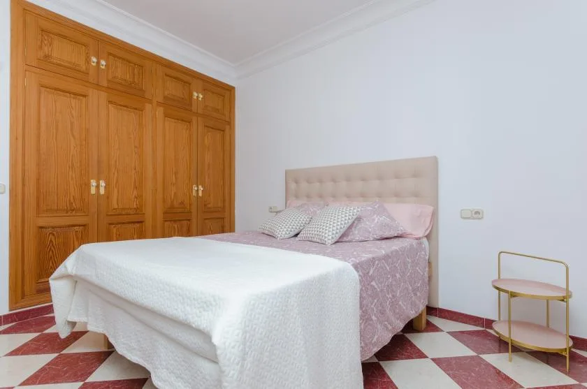 A bedroom with a bed, built-in wooden wardrobes, and a small side table.