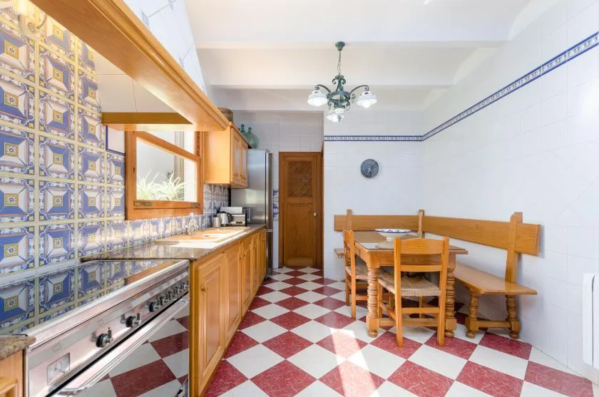 A tiled kitchen with wooden cabinets and a dining table.
