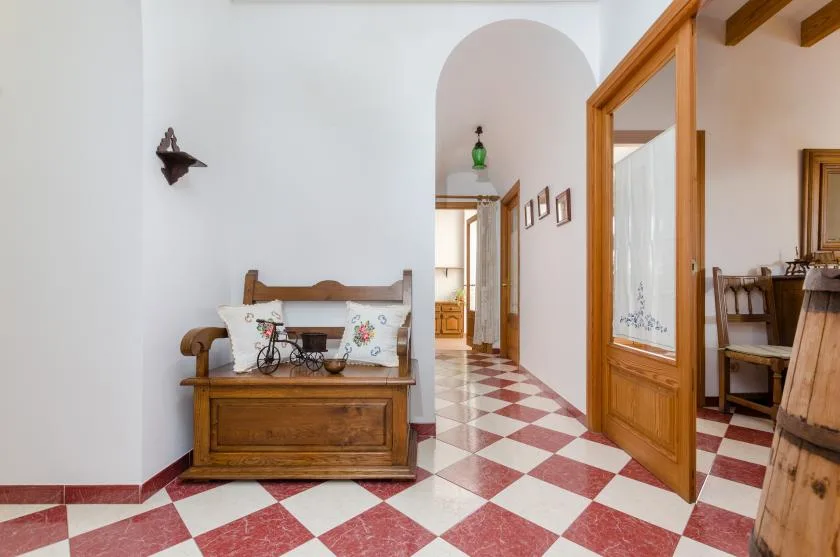 A tiled interior hallway with wooden furniture and an open wooden doorway.
