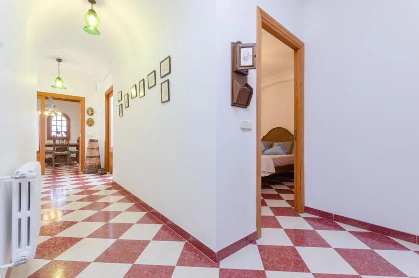 A tiled hallway leads to an open doorway with a bedroom visible beyond.