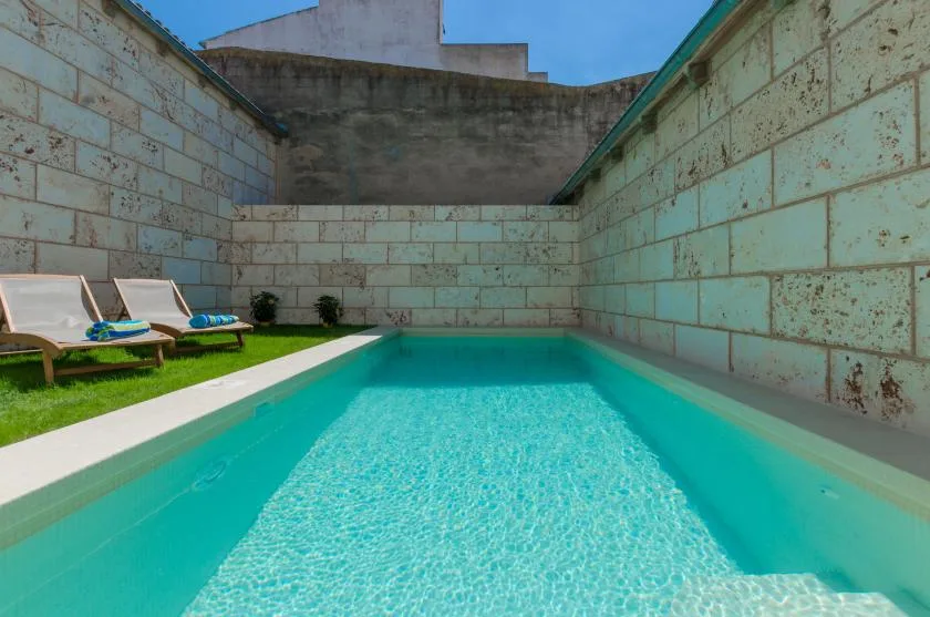 A small outdoor swimming pool beside a grassy area with lounge seating.